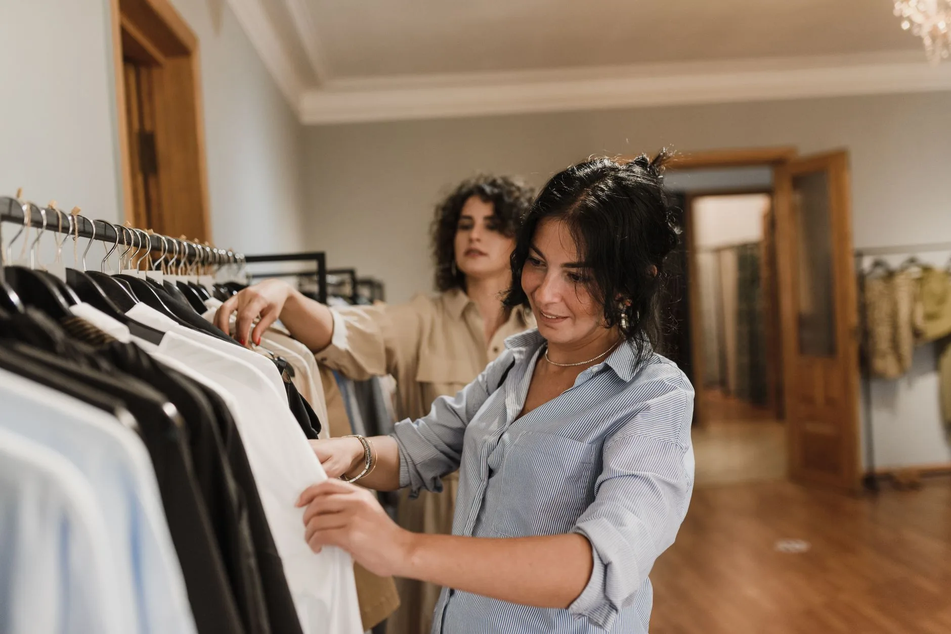 Cliente escolhendo roupas em uma arara da boutique