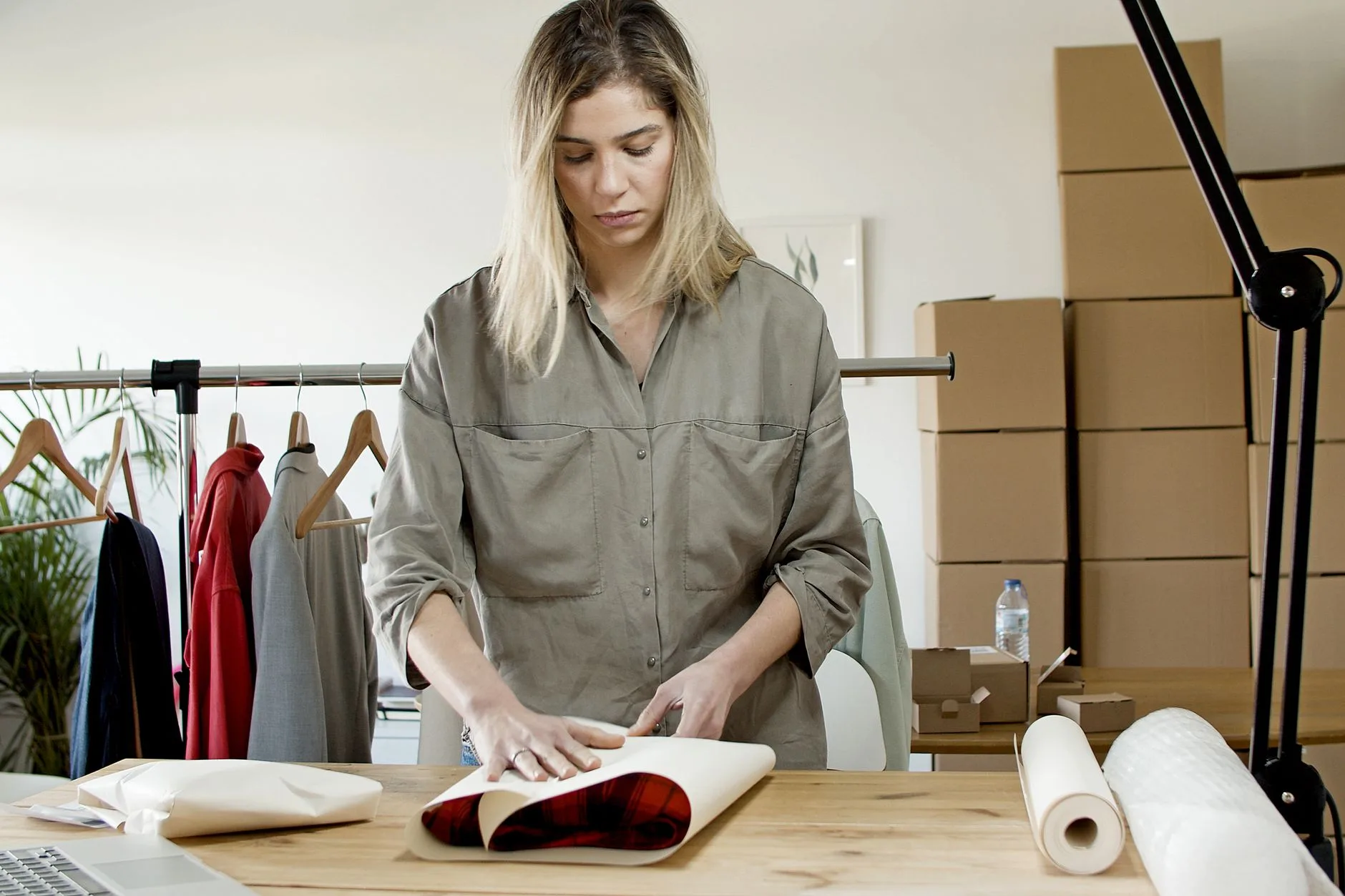 Mulher embalando pedidos de roupas em caixas