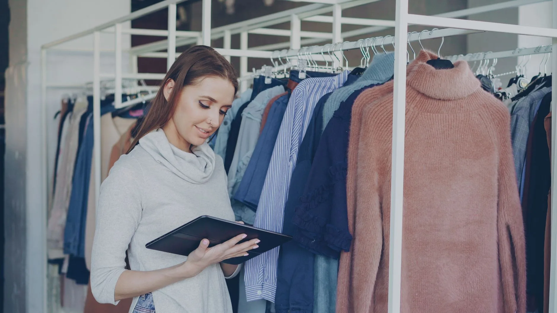 Mulher conferindo estoque de roupas em um tablet